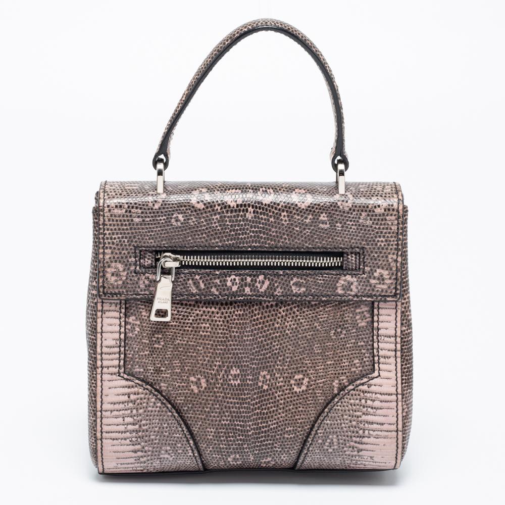 This elegant Prada bag is perfect for your next outing to town. It is made of high-quality leather and can match a day or evening outfit. It has a long crossbody chain, a top handle, and a lined interior secured by a metal lock on the