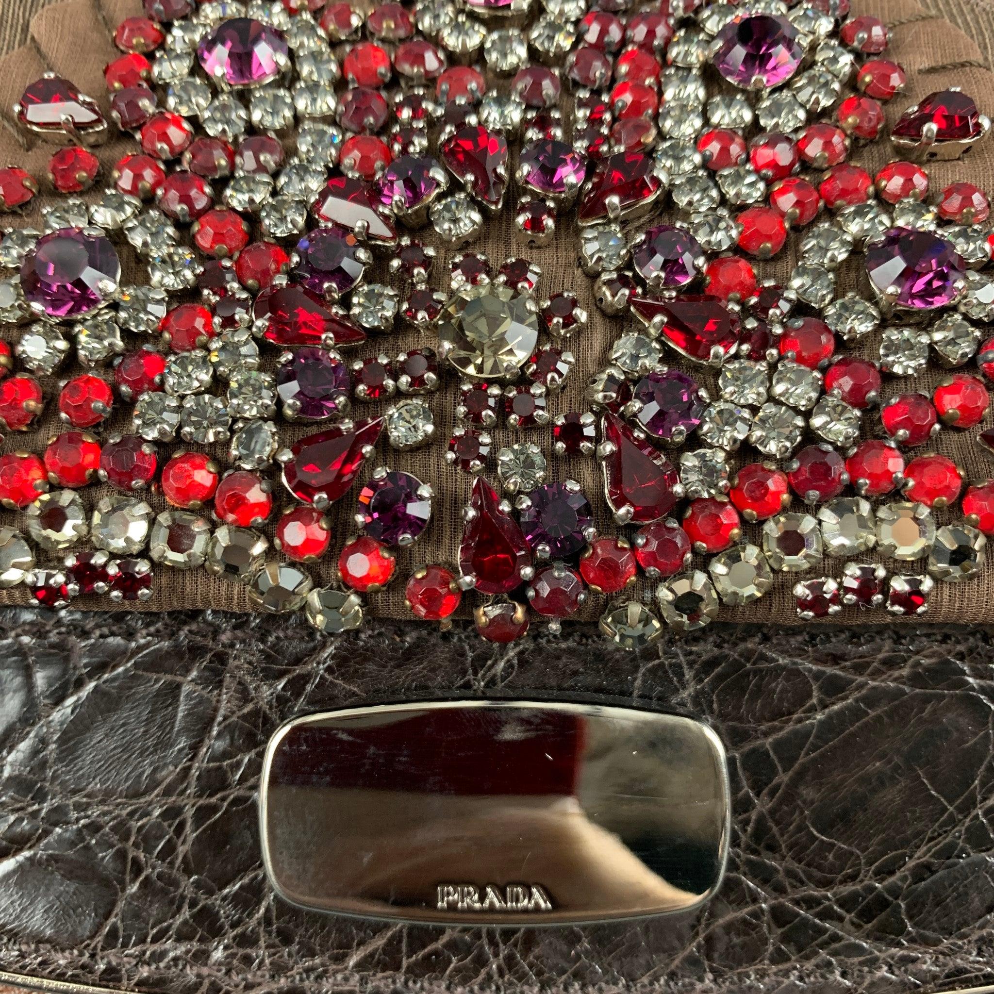 PRADA ANTIC SKIPPER+C handbag comes in a brown leather featuring a red rhinestones embellished, detachable strap, alligator leather panel, inner pocket, and a push open closure. Made in Italy. Comes with Dust Bag.Very Good Pre-Owned Condition. Light