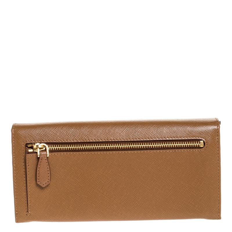 Store your essentials effortlessly in this sturdy continental wallet by Prada. Crafted from Saffiano leather, it comes in a lovely shade of brown. It is styled with a front flap with the brand logo that opens to reveal a leather and fabric interior