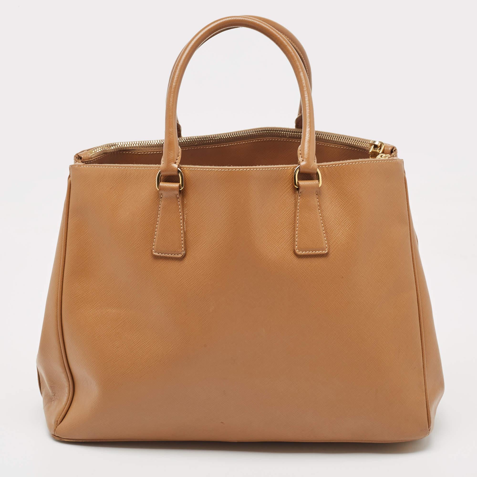 Feminine in shape and grand in design, this Double Zip tote by Prada will be a valuable addition to your closet. It has been crafted from Saffiano leather and styled minimally with gold-tone hardware. It comes with dual handles at the top, two zip
