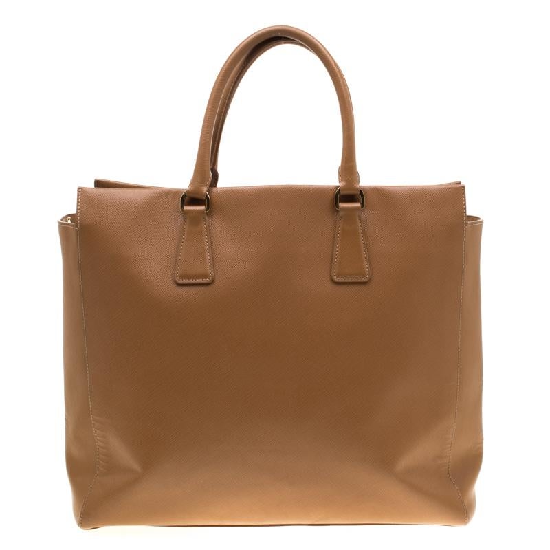Elevate your style quotient to a whole new level with this brown bag from Prada! The North/South bag comes crafted from Saffiano leather and styled with dual rolled top handles carrying an attached clochette. It features a gold-tone brand logo