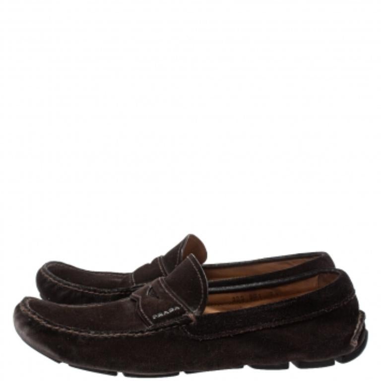 This pair of Prada penny loafers combines comfort with style. Crafted from brown suede, they feature a round toe, penny keeper strap, leather-lined insole, and rubber sole. This pair can be teamed up with office and casual attires.
