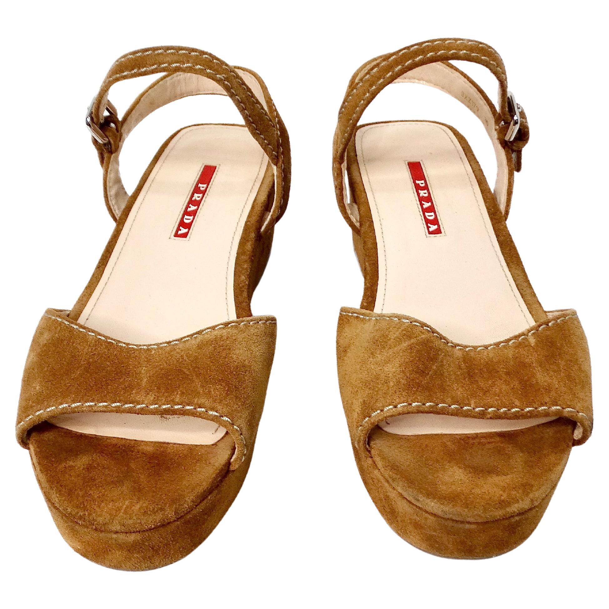 I sandali con zeppa in camoscio marrone di Prada sono l'epitome delle calzature di lusso, che uniscono un design sofisticato a un comfort senza pari. Realizzati in caldo camoscio marrone, questi sandali sono caratterizzati da un'elegante suola con