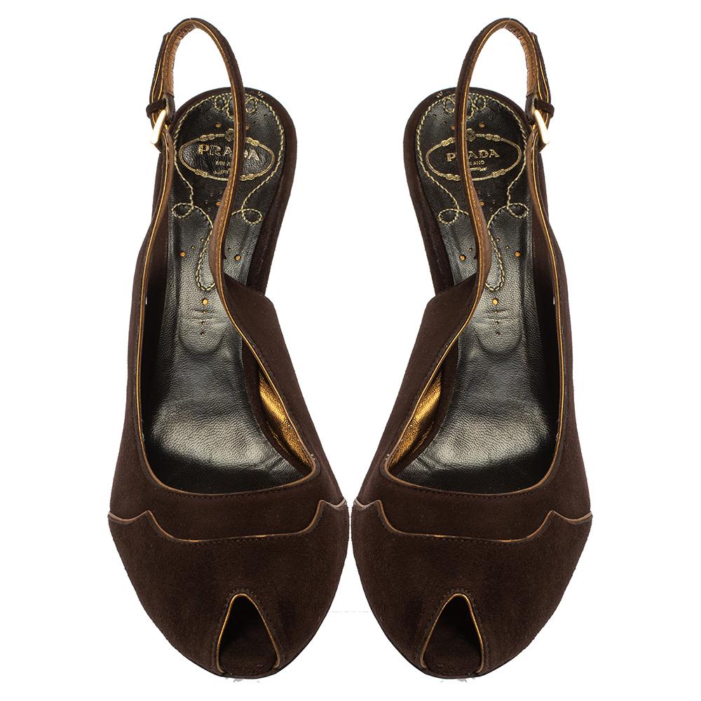 Conçues dans un design chic et classe, ces sandales Prada sont fabriquées en daim brun. Elles sont ornées d'orteils en peep, fixées par des lanières à la cheville et montées sur de confortables talons compensés.

