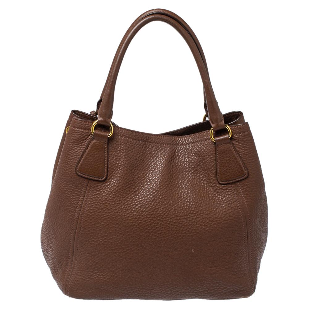 Masterfully crafted using brown Daino leather, this bag will make a loved addition. The Prada bag is held by two handles, equipped with metal feet and a nylon interior, and finished with the logo on the front. This is a one-stop fashion accessory