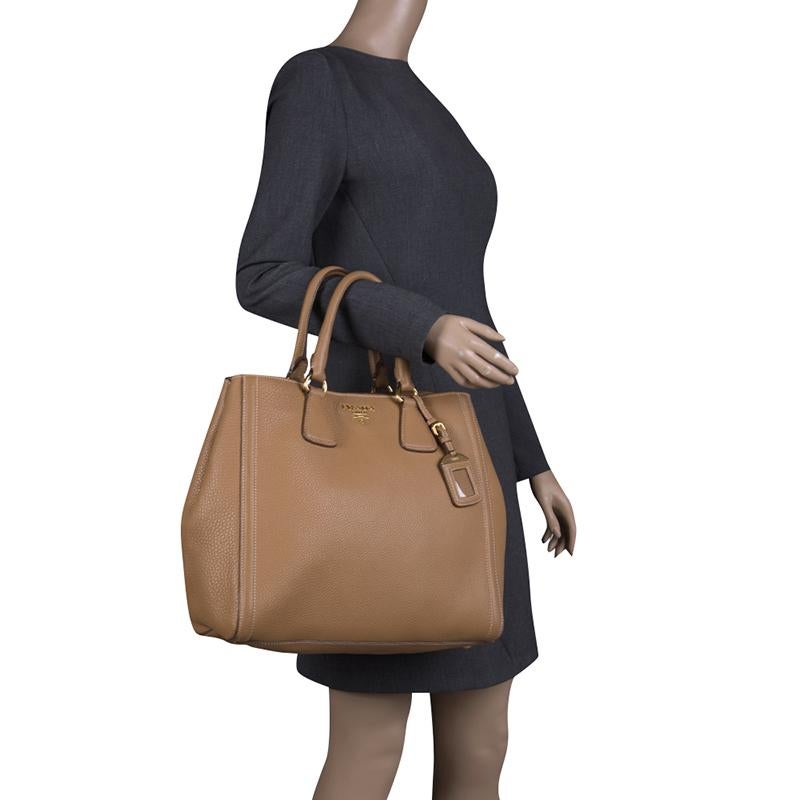 This covetable shopper tote from Prada will complement both your casual and formal attire. This Italian creation comes crafted in leather bearing the brand’s logo in gold-tone hardware on the subdued brown base. The design features double handles