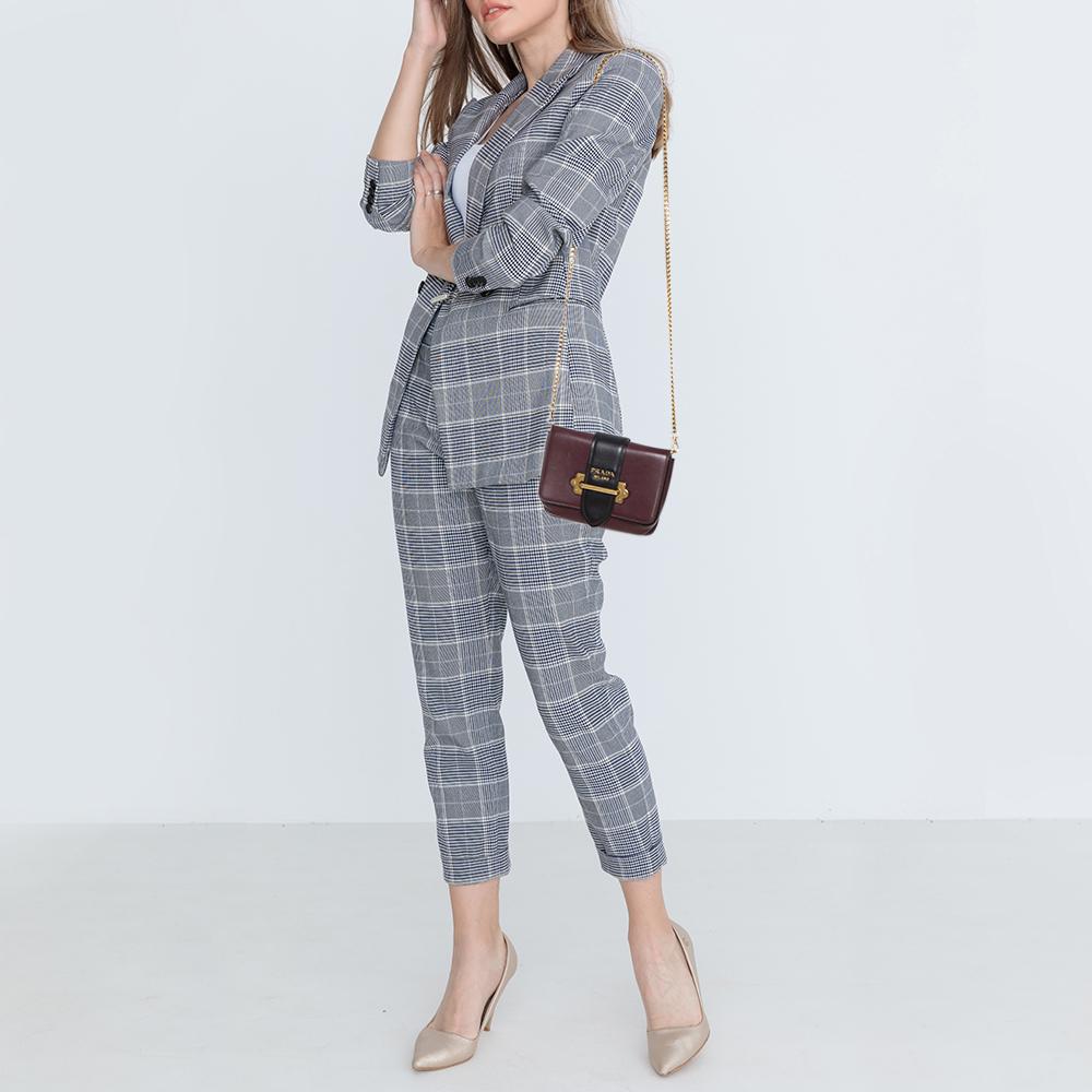 Inspired by valuable books from ancient times, the Cahier by Prada is a best-seller. This belt bag is crafted in Italy with black and burgundy leather. It features a gold-tone loop at the front that adds a touch of contrast. The strap closure with