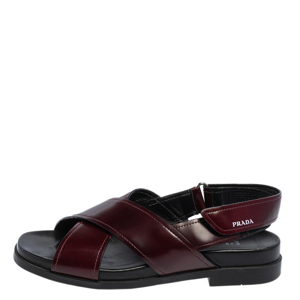 An elegant and chic pair of sandals from Prada that offers an upgrade to your style. Look fabulous in this pair of sandals, crafted out of leather and styled with crisscross vamp straps These burgundy and black flat sandals are equipped with