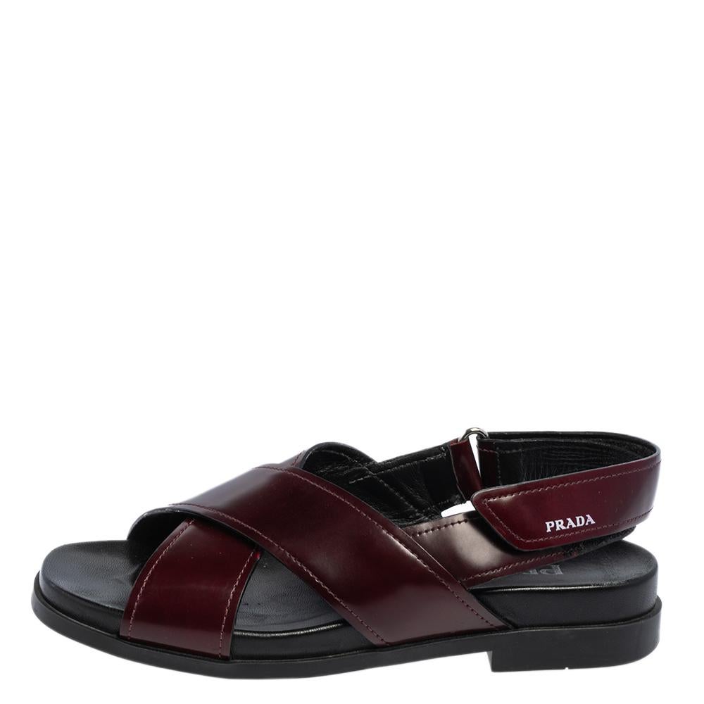 Ein elegantes und schickes Paar Sandalen von Prada, das Ihrem Stil ein Upgrade verleiht. Diese flachen Sandalen in Burgund und Schwarz sind aus Leder gefertigt und mit überkreuzten Riemen am Vorderblatt ausgestattet.

