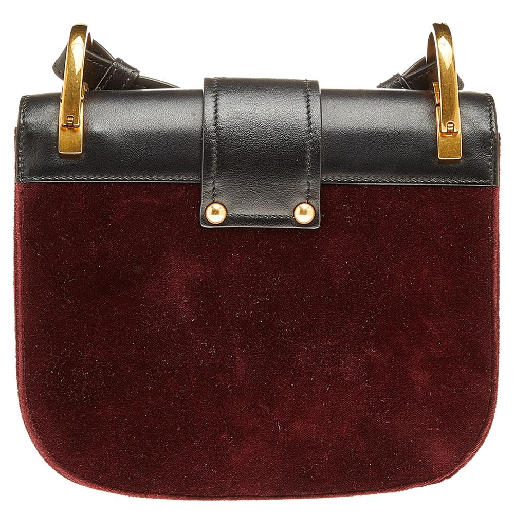 This stylish and luxurious crossbody bag is unmistakably Prada. It is crafted in Italy and made from velvet and leather. The burgundy and black hues add interest while the tuck-in strap adds security. The gold-tone hardware details to the spacious