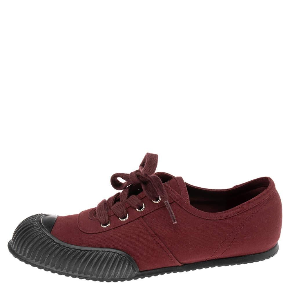 Coming in a classic low top silhouette  these Prada sneakers are a seamless combination of luxury  comfort  and style. They are made from canvas in the burgundy shade. These sneakers are designed with logo details  laced up vamps  and comfortable