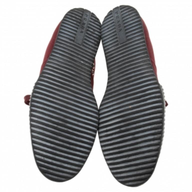 Coming in a classic low-top silhouette, these Prada sneakers are a seamless combination of luxury, comfort, and style. They are made from canvas in the burgundy shade. These sneakers are designed with logo details, laced-up vamps, and comfortable