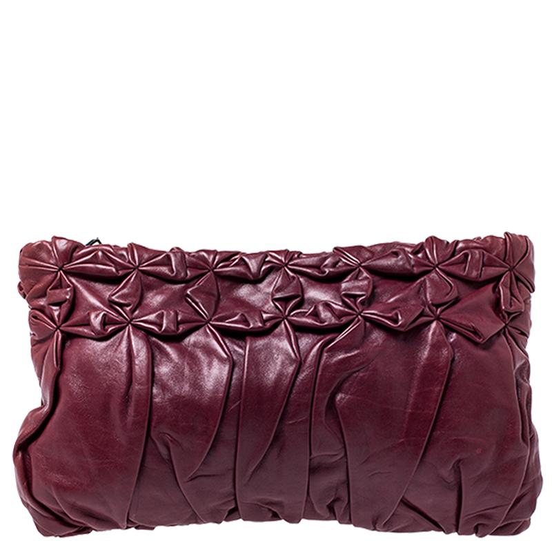 A stylish clutch is an everyday staple for all fashionistas! This creation from the house of Prada is crafted from burgundy leather. The piece is equipped with a zip top closure that reveals a well sized compartment and has a slip pocket. This