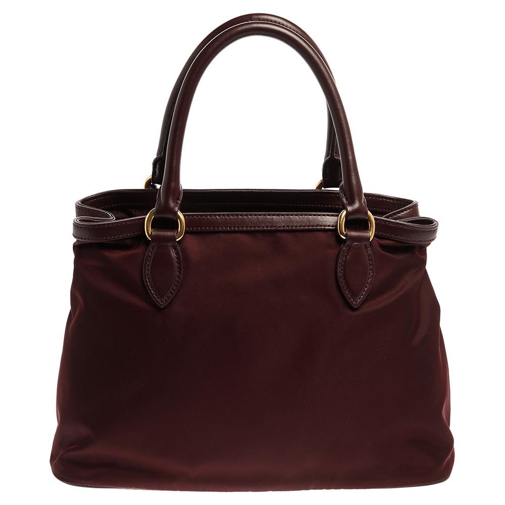 This Prada Borsa A Mano tote brings such a lovely shape that you're sure to look fashionable whenever you carry it. It has been crafted from burgundy nylon and leather and designed with two handles and a spacious nylon interior. This bag, complete