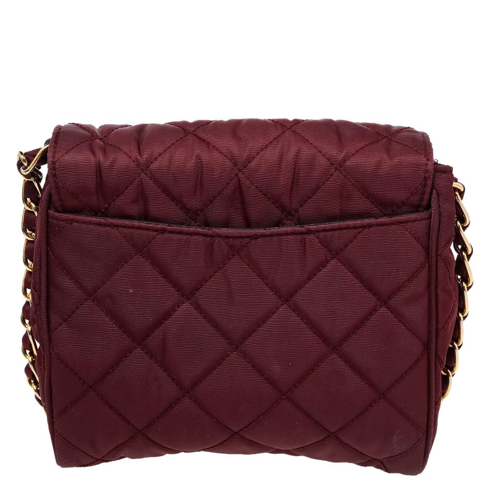 This piece from Prada is a perfect balance of elegance and practical utility. The burgundy bag is made from quilted nylon and flaunts an interwoven chain strap. It features a push-lock closure that leads to a well-sized interior capable of holding