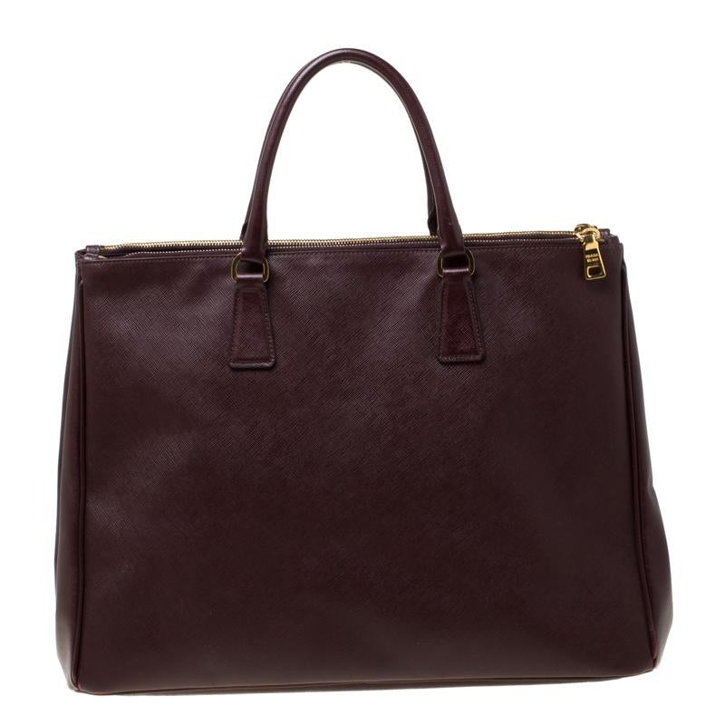 Feminine in shape and grand on design, this Double Zip tote by Prada will be a loved addition to your closet. It has been crafted from Saffiano leather and styled minimally with gold-tone hardware. It comes with two top handles, two zip compartments