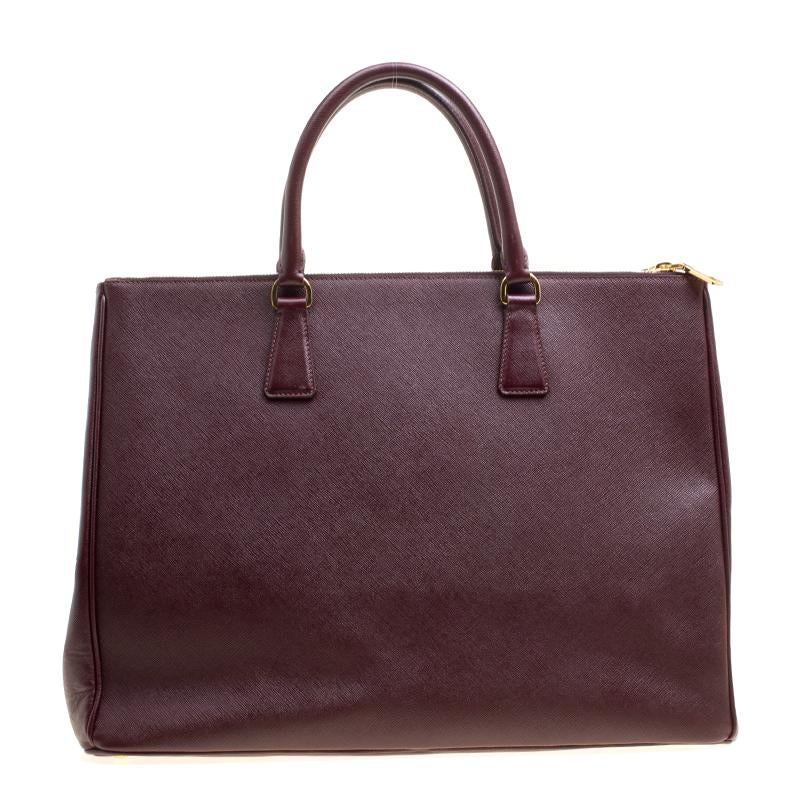 For women with an on-the-go lifestyle, this Executive Double Zip tote from the house of Prada is an elegant option. Masterfully designed, it is rendered in burgundy Saffiano Lux leather and adorned with gold-tone hardware. The bag opens to an