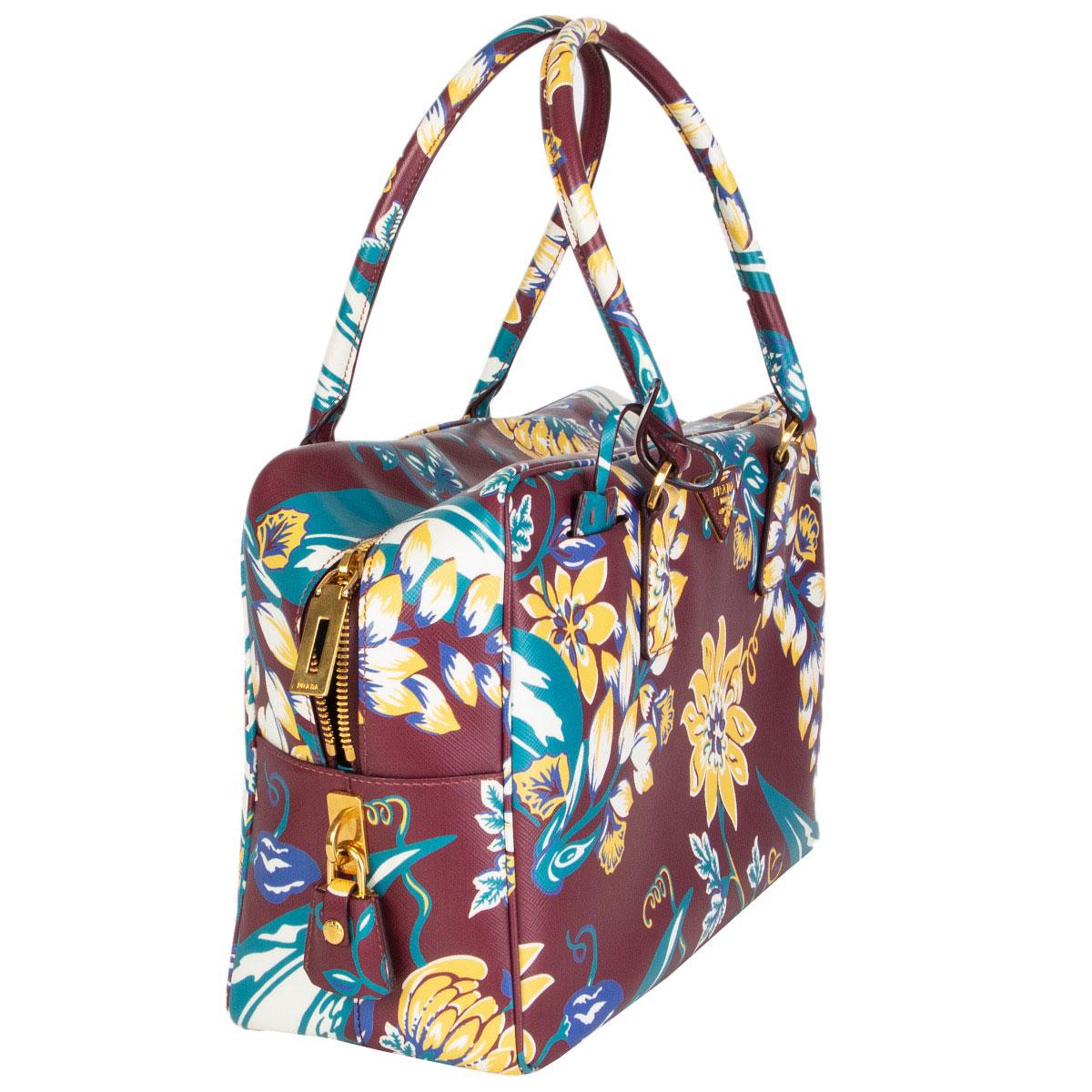 100% authentic Prada flower print Bauletto handbag in burgundy, yellow, white, blue and turquoise Saffiano leather (100%). Closes with a zipper on top and is lined in turquoise calfskin leather (100%) with some profiles in flower print Saffiano