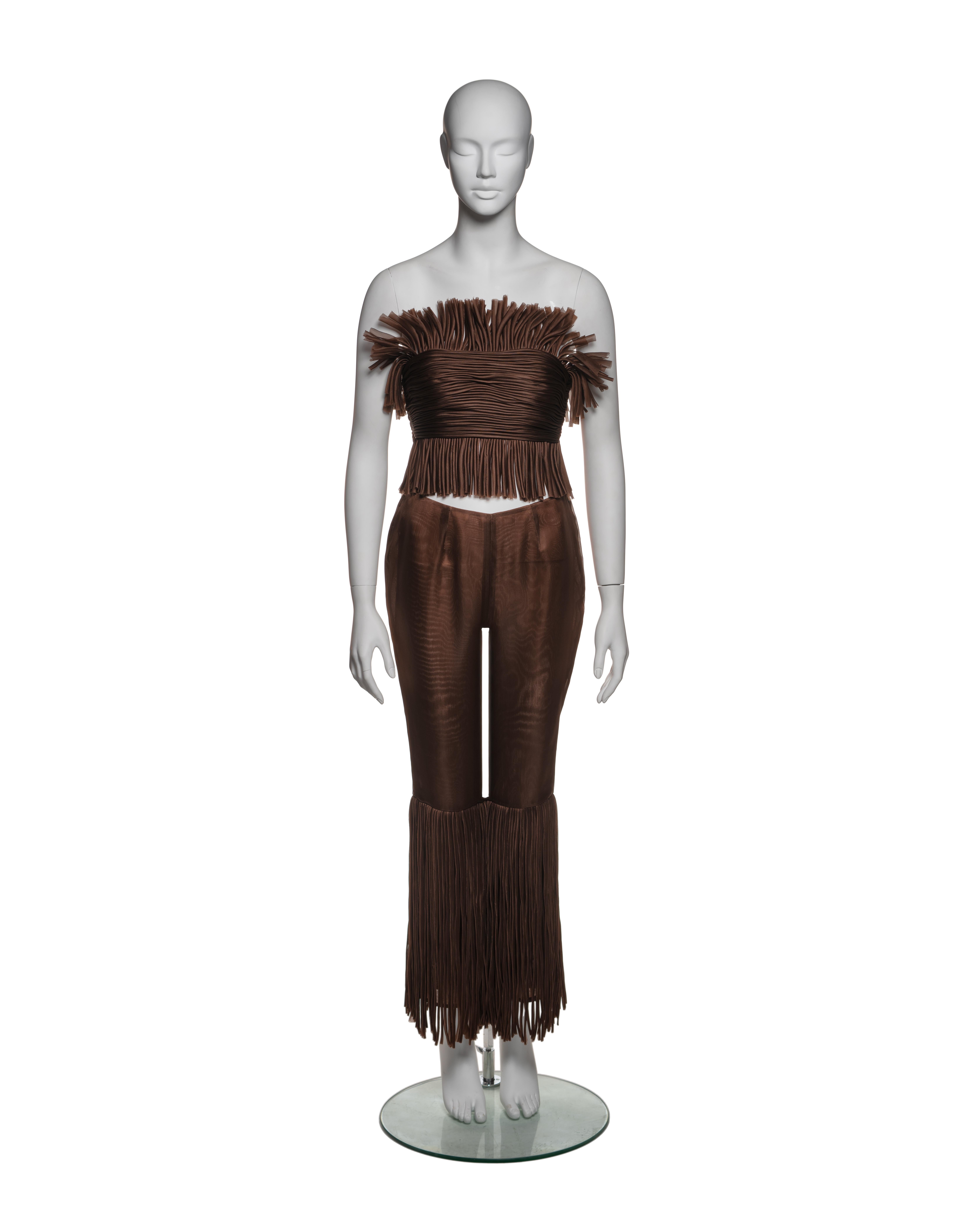 Questo primo disegno di Miuccia Prada mostra il suo uso sperimentale di materiali e texture. Il top senza spalline è realizzato in organza di seta marrone ed è costruito in modo unico con file di nastri di organza tubolari, che sono accuratamente