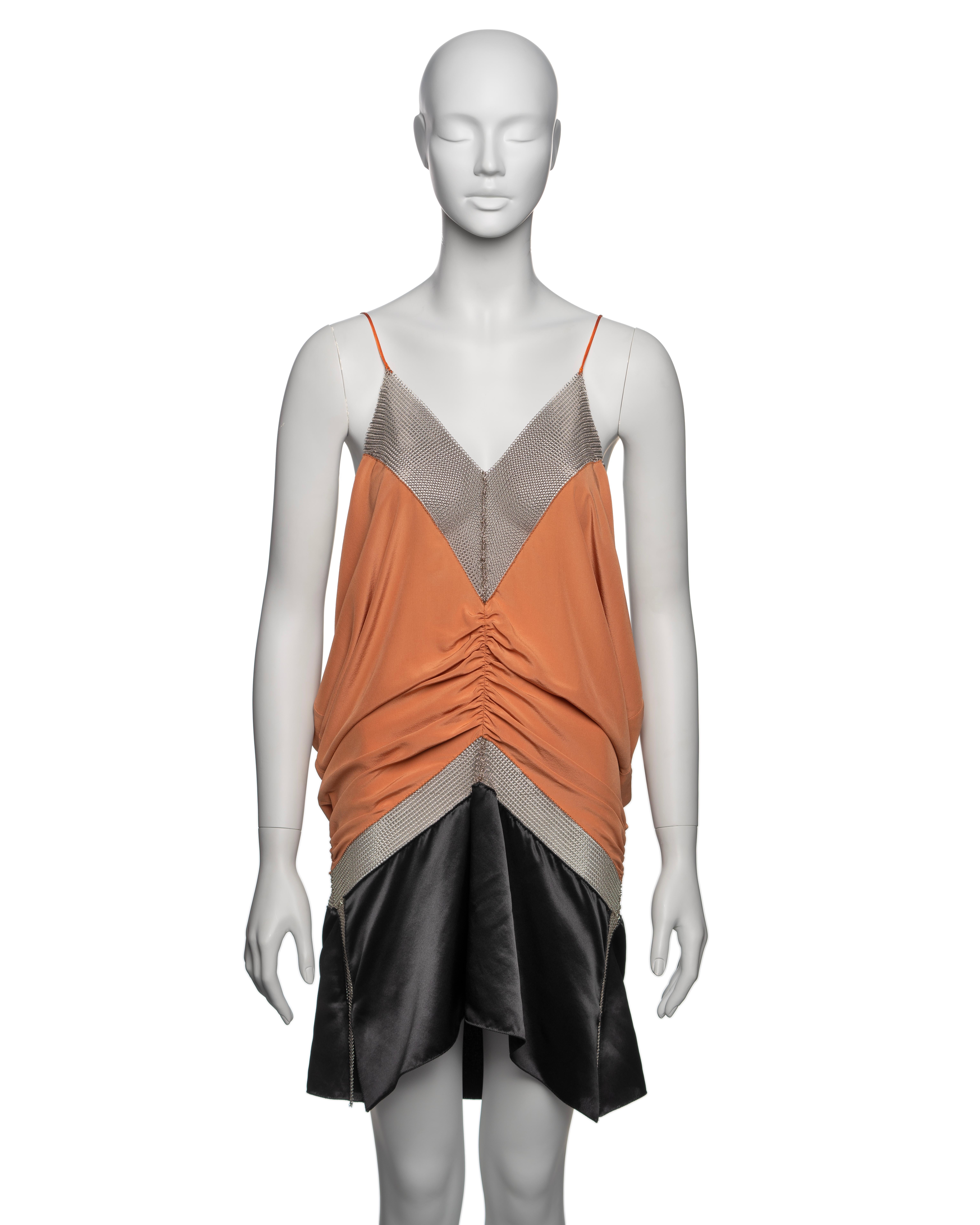 ▪ Brand: Prada
▪ Creative Director: Miuccia Prada
▪ Collection: Fall-Winter 2002
▪ Fabric: Silk, Chainmail 
▪ Details: The dress features v-shaped chainmail inserts, a soft orange silk bodice with a ruched seam at the centre, creating a drape. The