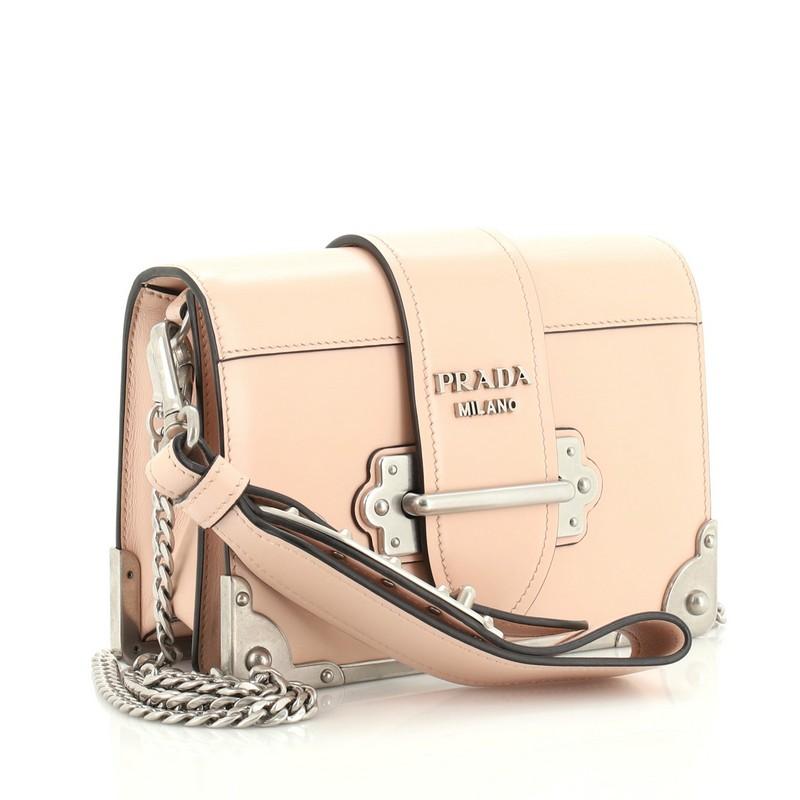This Prada Cahier Chain Crossbody Bag City Calf Small, crafted in pink city calf leather, features a chain link strap with leather pad, metal trim, and matte silver-tone hardware. Its front flap with buckle closure opens to a black leather interior