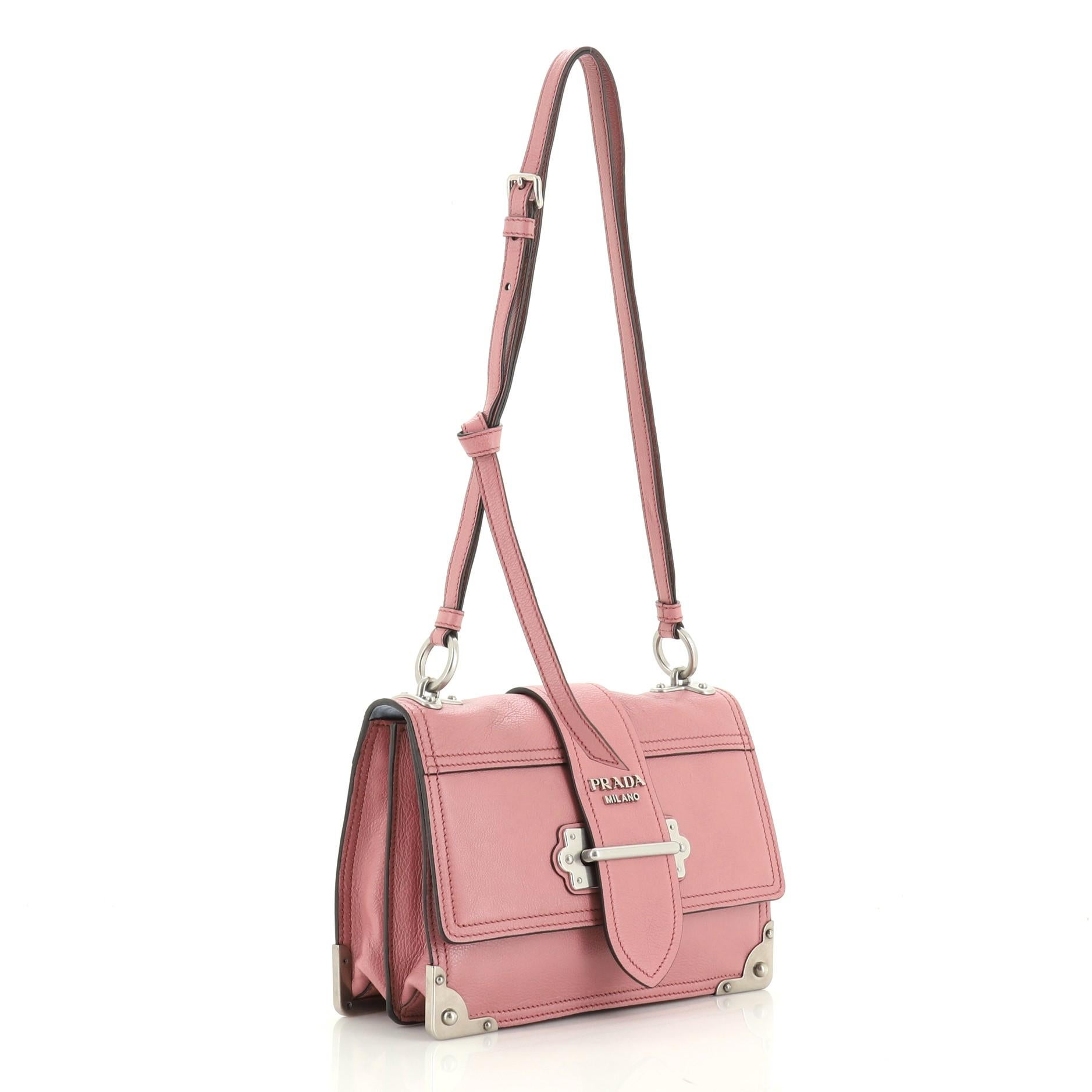 This Prada Cahier Convertible Shoulder Bag City Calf Medium, crafted from pink calf leather, features a flat leather strap, metal hardware trim, and aged silver-tone hardware. Its buckle closure opens to a blue suede interior with side zip and slip