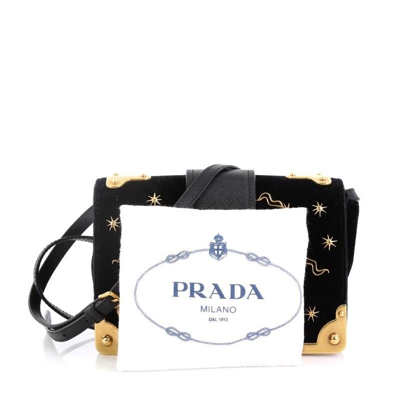 This Prada Cahier Crossbody Bag Embellished Velvet Small, crafted from black velvet, features adjustable leather strap, metal hardware trim, star and moon detailing, and gold-tone hardware. Its buckle closure opens to a black leather interior with