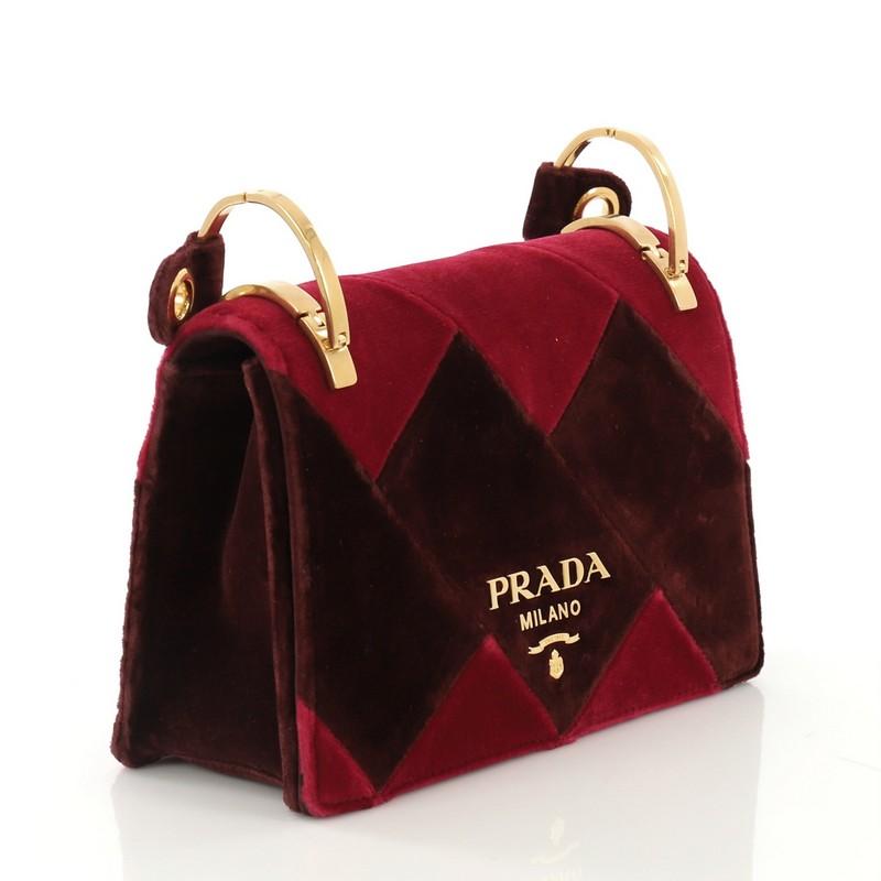 This Prada Cahier Shoulder Bag Velvet Small, crafted in purple and burgundy velvet, features shoulder strap and gold-tone hardware. Its flap opens to a black fabric and purple velvet interior with slip pockets. 

Estimated Retail Price: