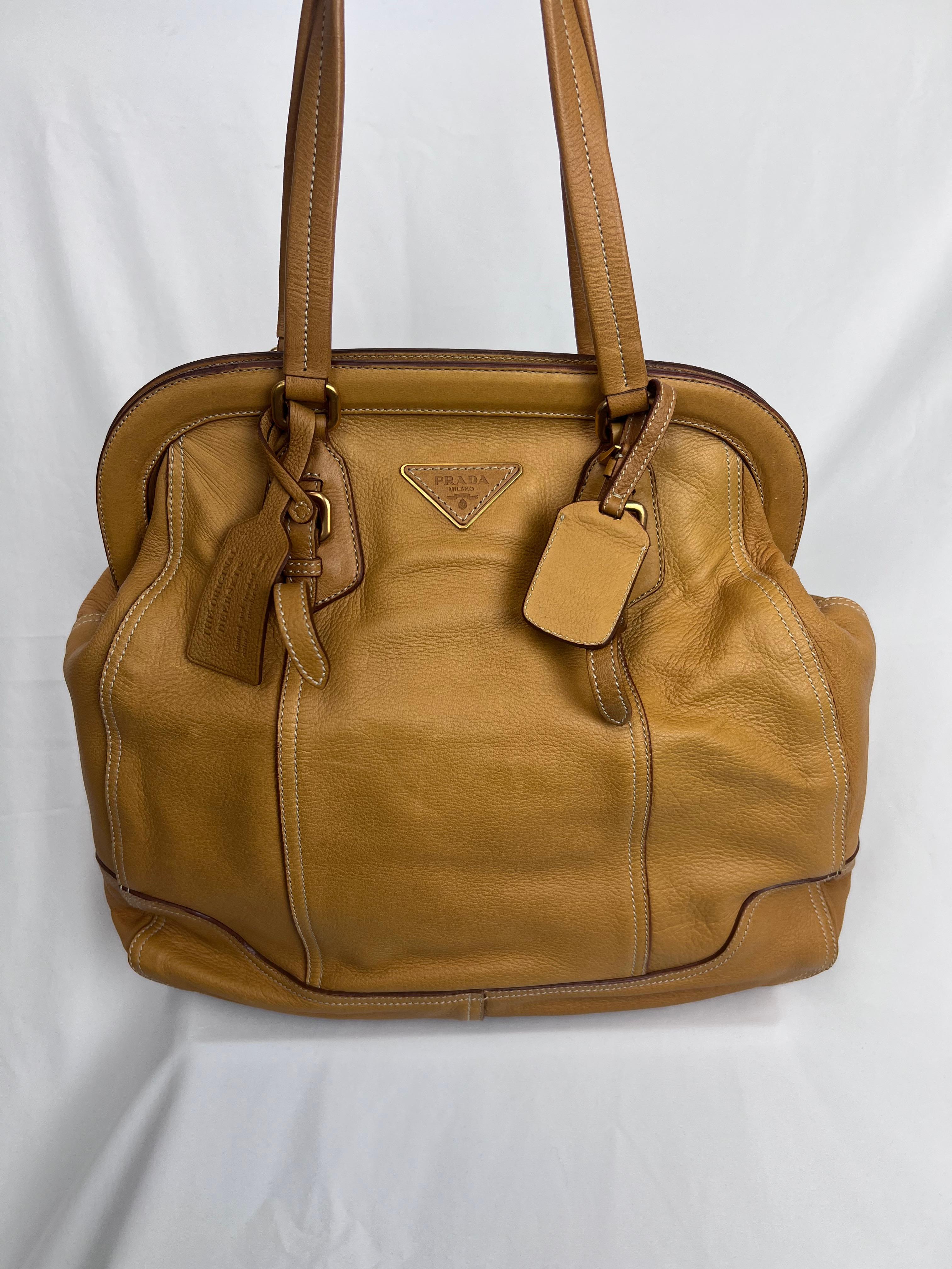 Timelessly elegant, the Prada Camel Leather High Doctor's Bag is a statement piece that exudes sophistication. Crafted from supple camel-tone calfskin leather, this structured bag takes inspiration from classic doctor's bags, combining vintage charm