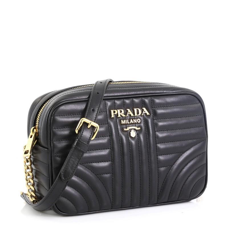 This Prada Camera Bag Diagramme Quilted Leather Small, crafted from black quilted leather, features a chain link strap and gold-tone hardware. Its zip closure opens to a black fabric interior with slip pocket. These are professional pictures of the