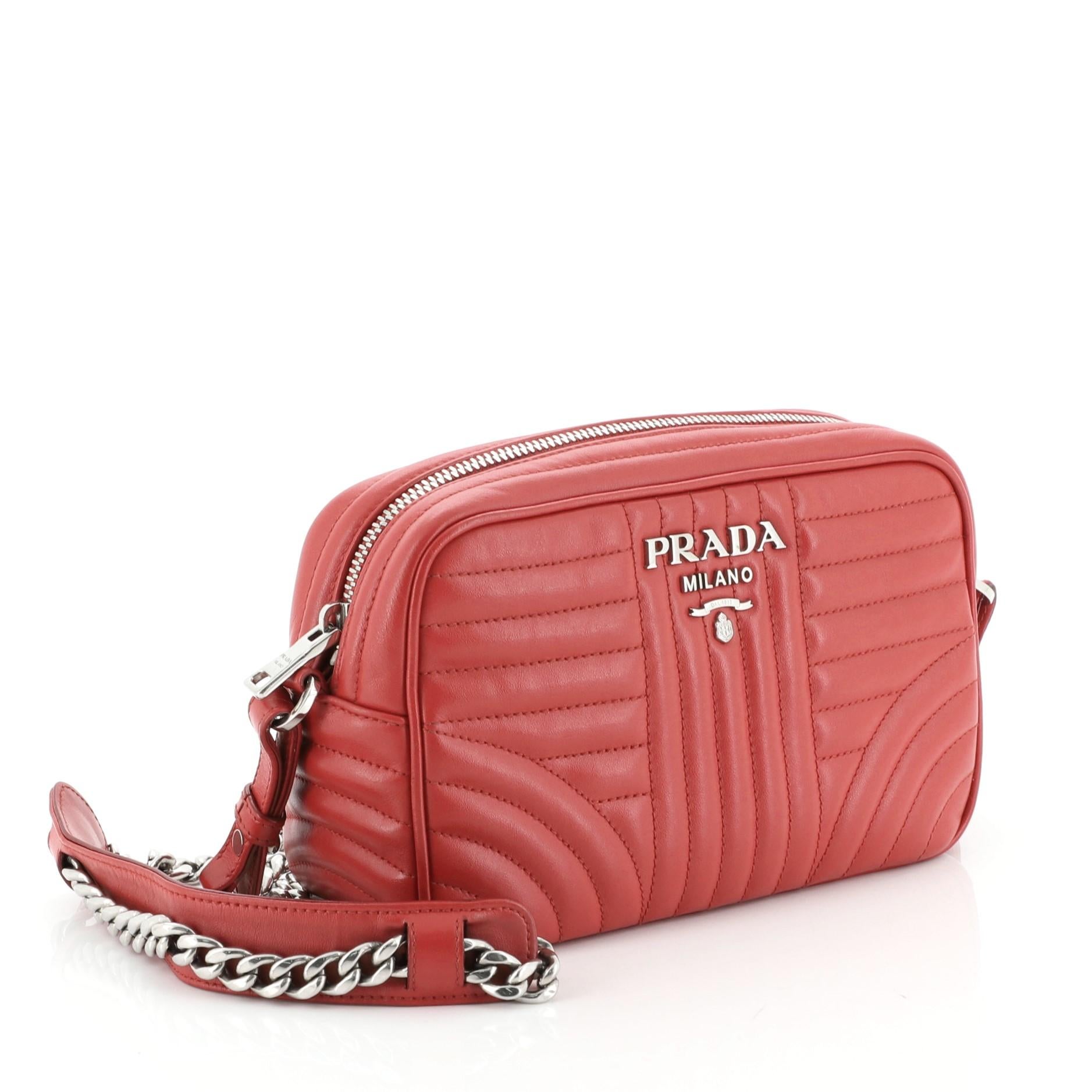 This Prada Camera Bag Diagramme Quilted Leather Small, crafted from red quilted leather, features a chain link strap and silver-tone hardware. Its zip closure opens to a red fabric interior with slip pocket. 

Estimated Retail Price: