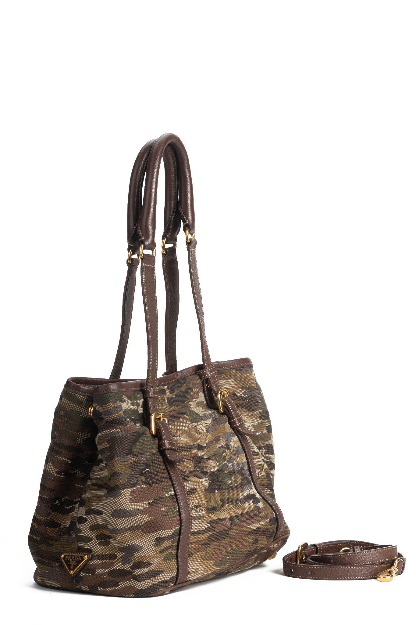 Prada military style tote bag. The bag has two large leather handles to wear it over the shoulder and comes also with a brown leather strap to wear it crossbody. The piece is made of fabric in a military pattern and trimmed with brown leather. The