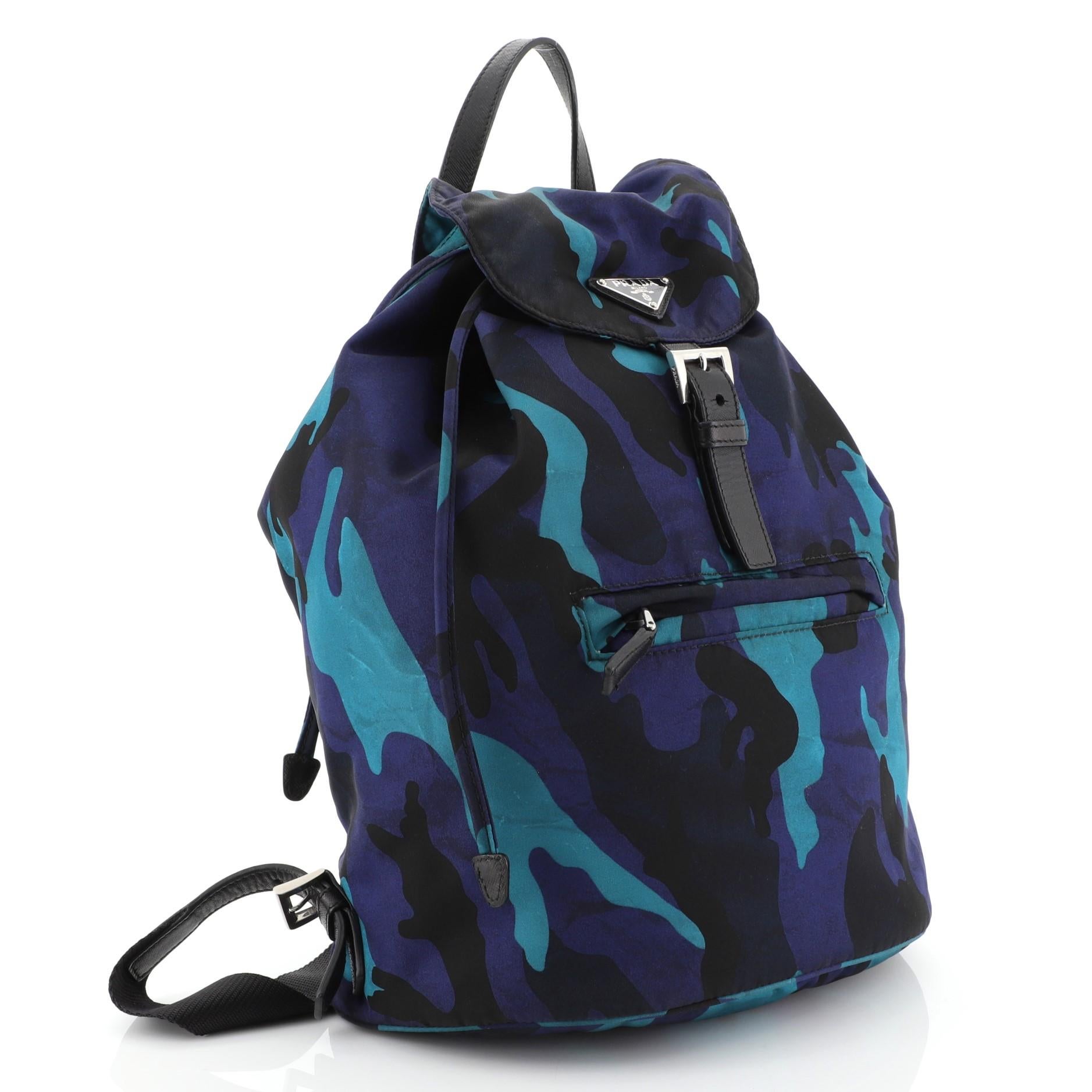 This Prada Camouflage Backpack Tessuto Large, crafted in blue Camouflage tessuto, features a top carry handle, adjustable back shoulder straps, buckle flap, exterior front zip pocket, and silver-tone hardware. Its drawstring closure opens to a black