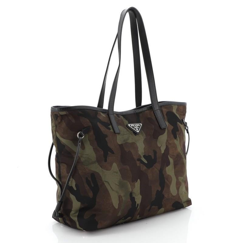 This Prada Camouflage Convertible Open Tote Tessuto Medium, crafted from brown and green camouflage tessuto, features dual leather handles, leather trim and silver-tone hardware. Its magnetic snap closure opens to a black fabric interior with side