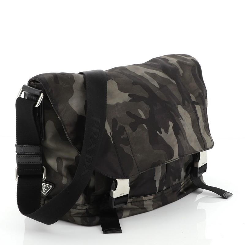 This Prada Camouflage Messenger Bag Tessuto Medium, crafted from green fabric, features an adjustable shoulder strap, exterior back zip pocket, and silver-tone hardware. Its flap and double buckle closure opens to a black fabric interior.