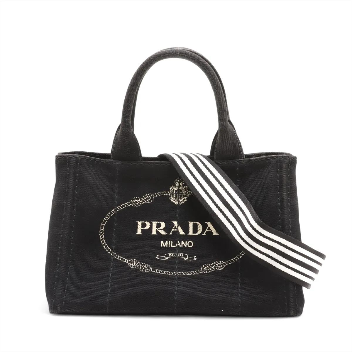 La borsa Prada Canapa Canvas x Leather Two-Way in nero incarna l'eleganza senza tempo e la raffinata maestria del marchio. Realizzata in tela resistente con lussuosi accenti in pelle, offre raffinatezza e praticità quotidiana. L'iconico logo Prada