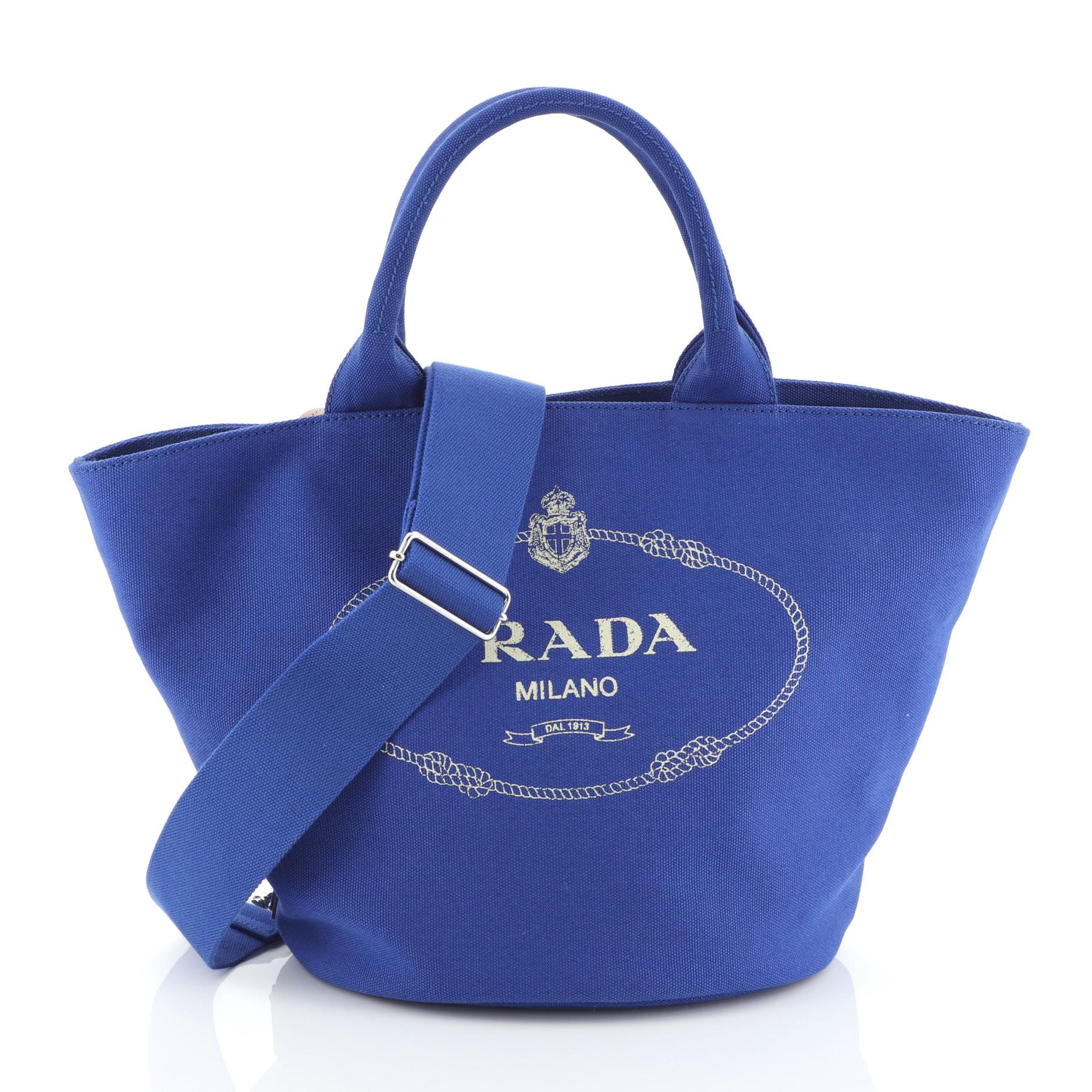 This Prada Canapa Convertible Shopping Tote Canvas Medium, crafted in blue canvas, features dual top handles and silver-tone hardware. It opens to a blue canvas interior with side zip pocket. 

Estimated Retail Price: $950
Condition: Great. Wear on