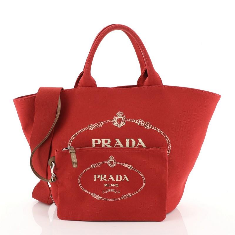 This Prada Canapa Convertible Shopping Tote Canvas Medium, crafted in red canvas, features dual top handles and silver-tone hardware. It opens to a red fabric interior with side zip pocket.

Condition: Excellent. Minor wear on base and handles,