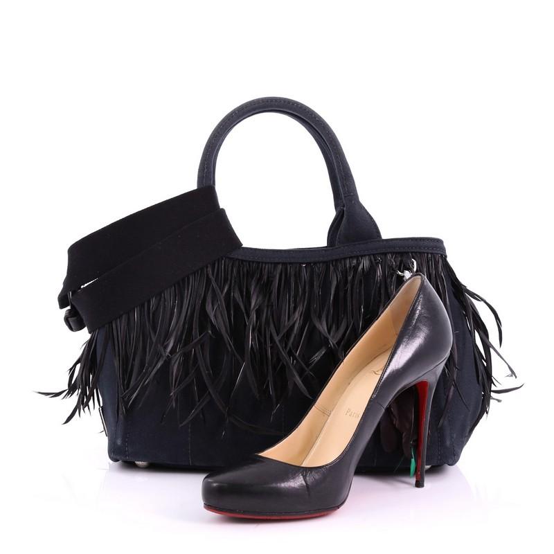 This Prada Canapa Convertible Tote Canvas and Feather Mini, crafted from black canvas and feathers, features dual rolled handles, raised Prada logo on the side, protective base studs, and silver-tone hardware. Its wide open top showcases a black