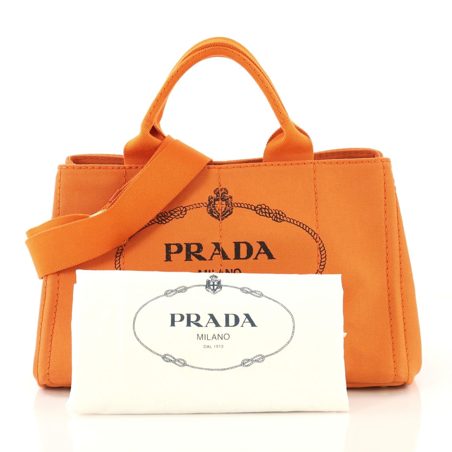 This Prada Canapa Convertible Tote Canvas Medium, crafted in orange canvas, features dual rolled handles, side snap buttons and gold-tone hardware. Its wide top opening showcases an orange canvas interior with side zip and slip pockets. 

Estimated
