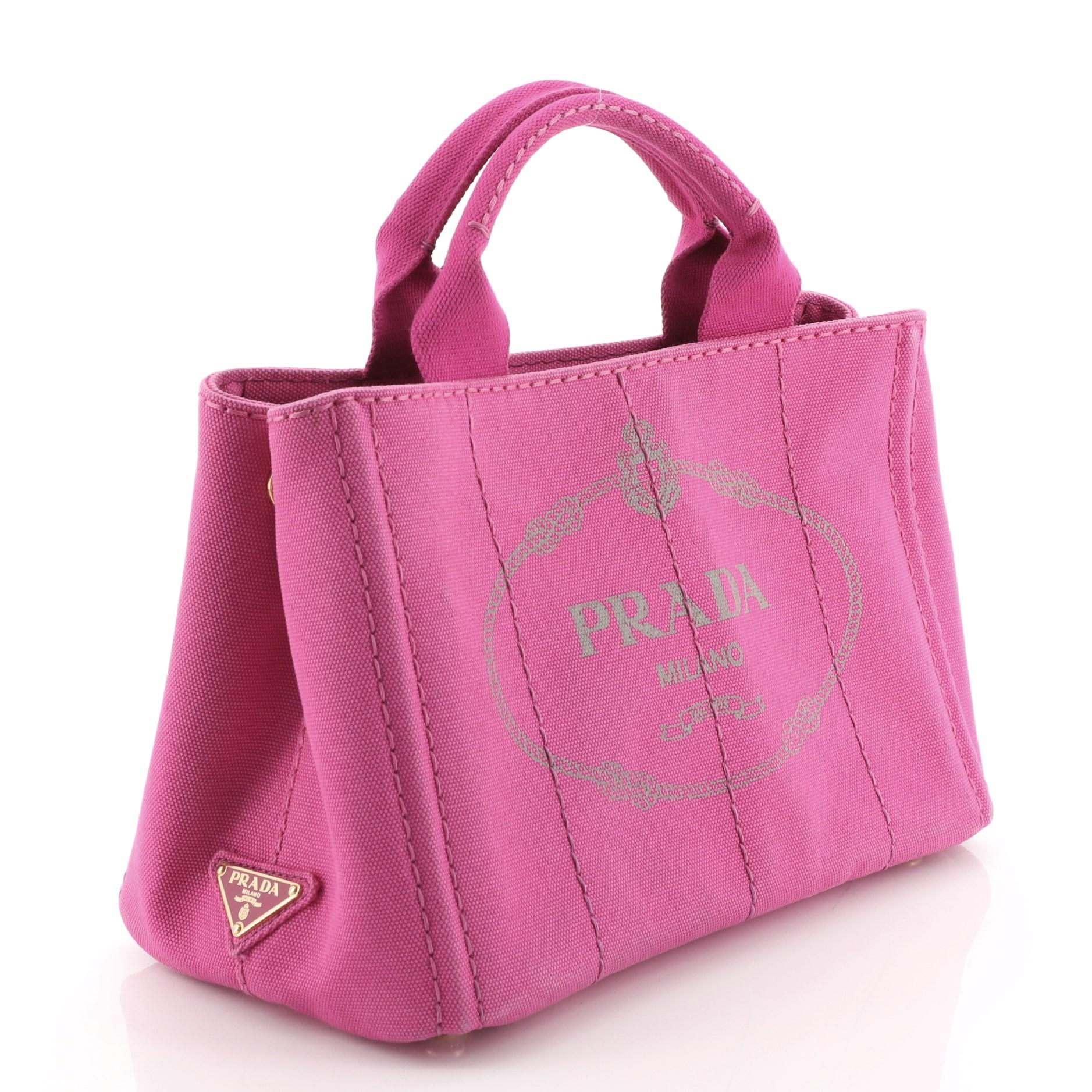 This Prada Canapa Convertible Tote Canvas Mini is a perfect everyday bag fit for the modern woman. Crafted from pink canvas, features dual rolled handles, side snap buttons, and gold-tone hardware. It opens to a pink canvas interior with zip and