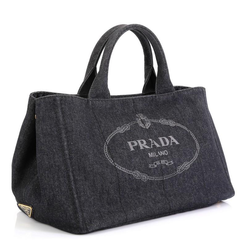 This Prada Canapa Convertible Tote Denim Medium, crafted in black denim, features dual rolled handles, side snap buttons and gold-tone hardware. Its wide top opening showcases a black denim interior with side zip and slip pockets. 
Estimated Retail