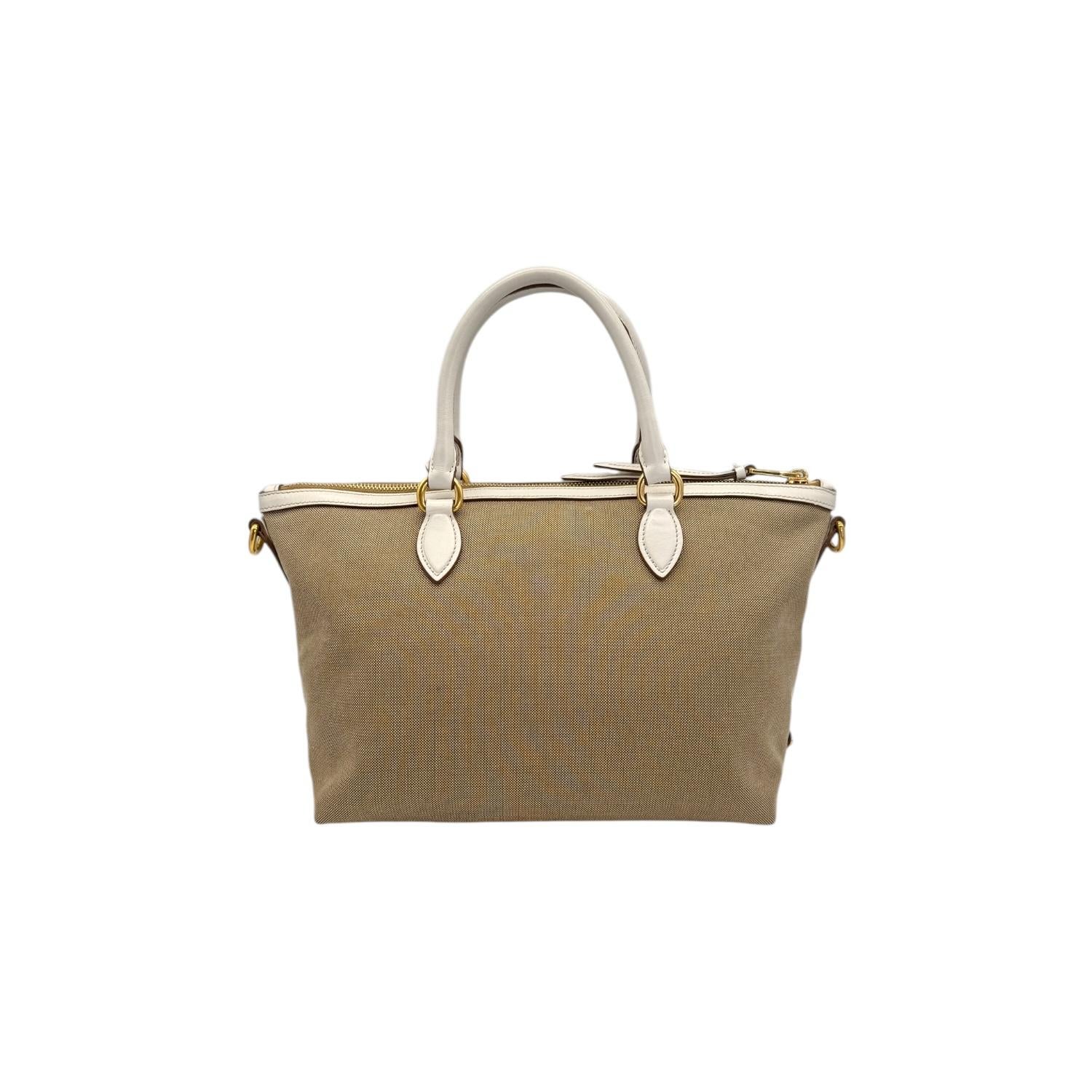 Élevez votre style avec le sac fourre-tout à poignée supérieure Prada Canapa. Fabriqué de manière experte en Turquie, le matériau en toile respire le luxe tandis que les accessoires en métal doré ajoutent une touche d'élégance. La fermeture à