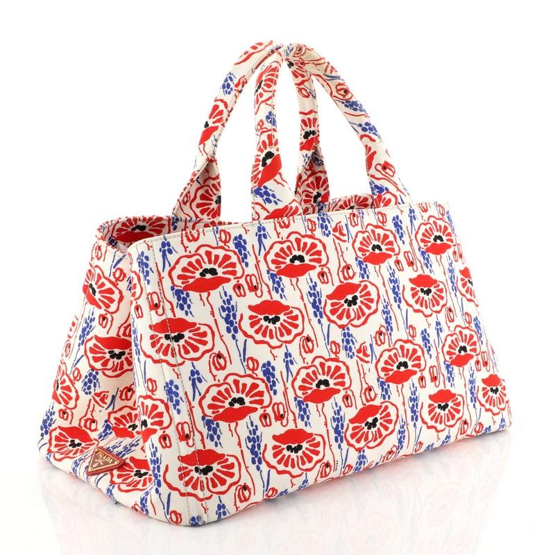 This Prada Canapa Tote Printed Canvas Large, crafted from white, blue and red canvas, features dual flat handles, side snap buttons, protective base studs and gold-tone hardware. Its wide open top opens to a red canvas interior with zip and slip