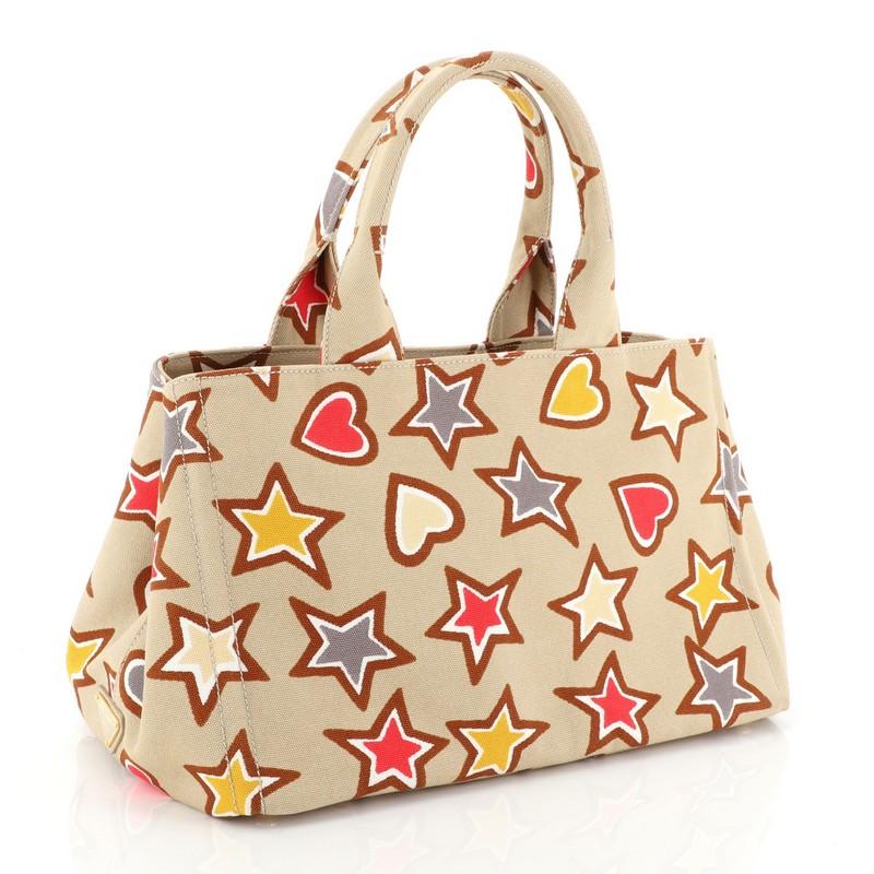 This Prada Canapa Tote Printed Canvas Medium, crafted from neutral printed canvas, features dual flat handles, side snap buttons, protective base studs and gold-tone hardware. Its wide open top opens to a neutral fabric interior with zip and slip