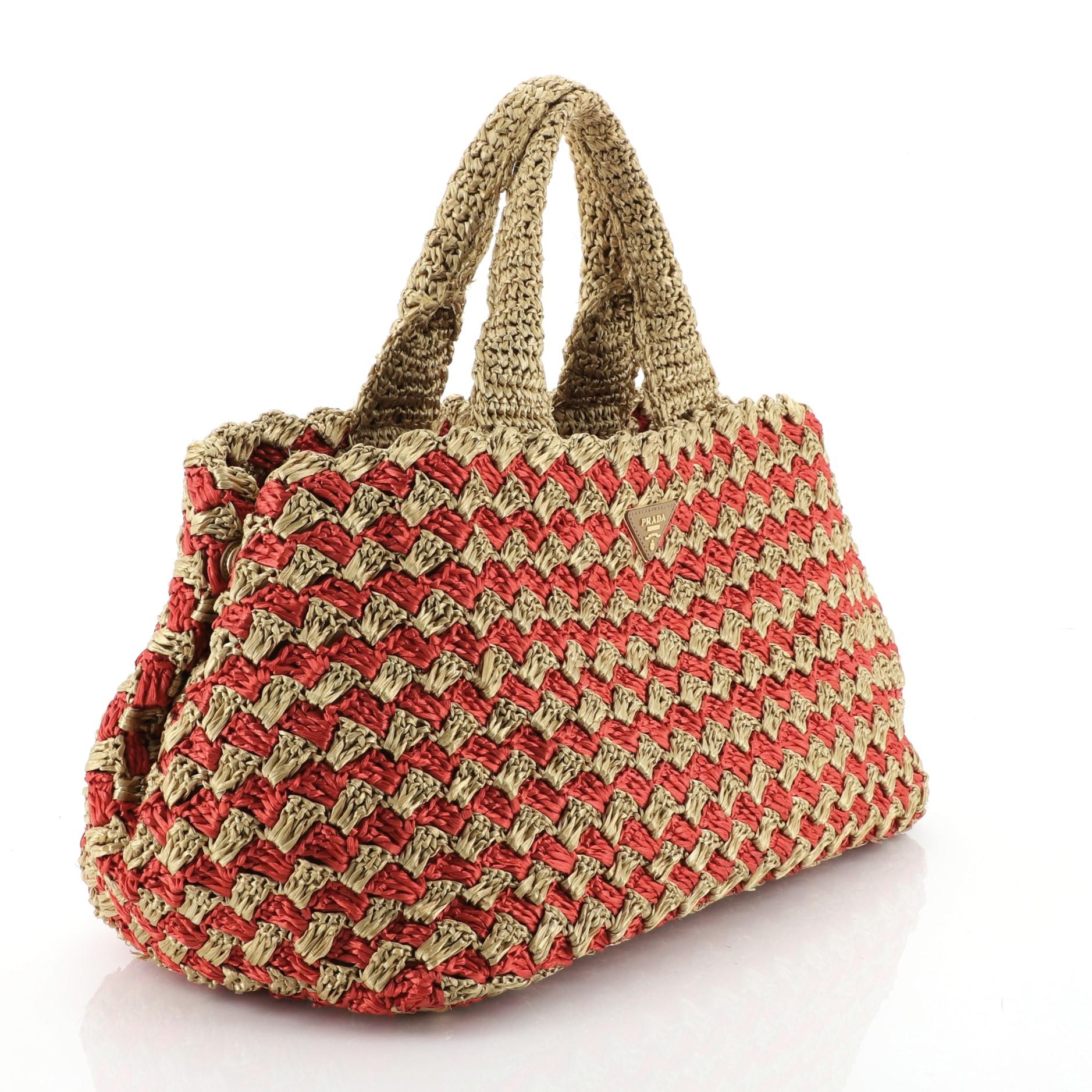 This Prada Canapa Tote Straw Medium, crafted in red and gold straw, features dual top handles and gold-tone hardware. It opens to a red fabric interior. 

Estimated Retail Price: $1,100
Condition: Very good. Wear and fraying on base corners and
