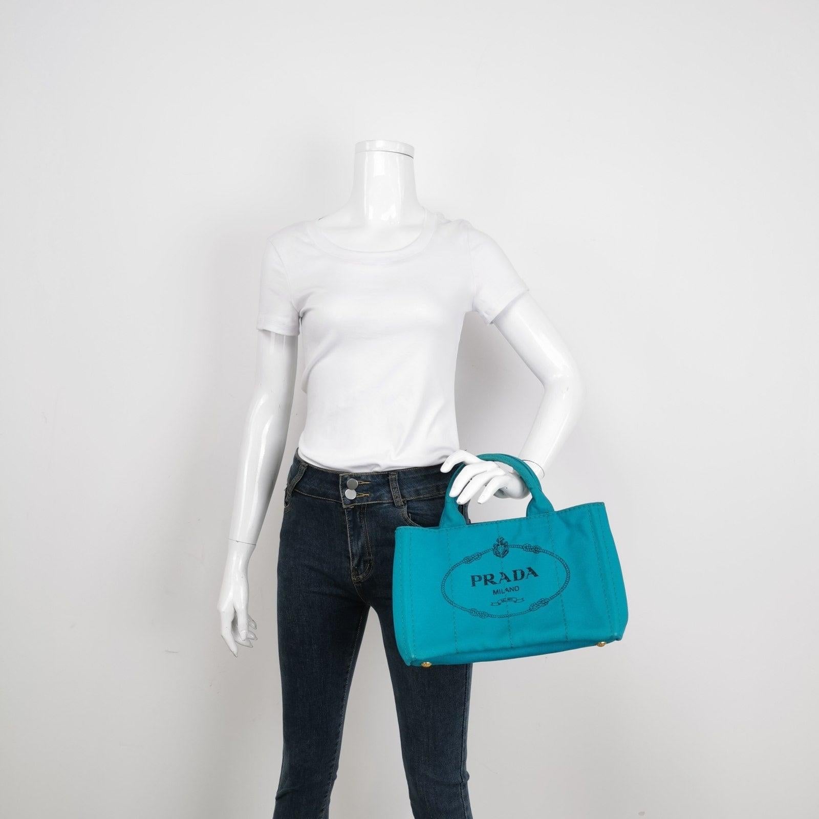 Prada Canape Canvas Tote Small Blue Top Handle Bag These are professional photos of the actual bag offered by Luxbags. Hemp fabric bag with silk-screened Prada logo and classic enamel triangle logo on the sides. Inside, three pockets and a light