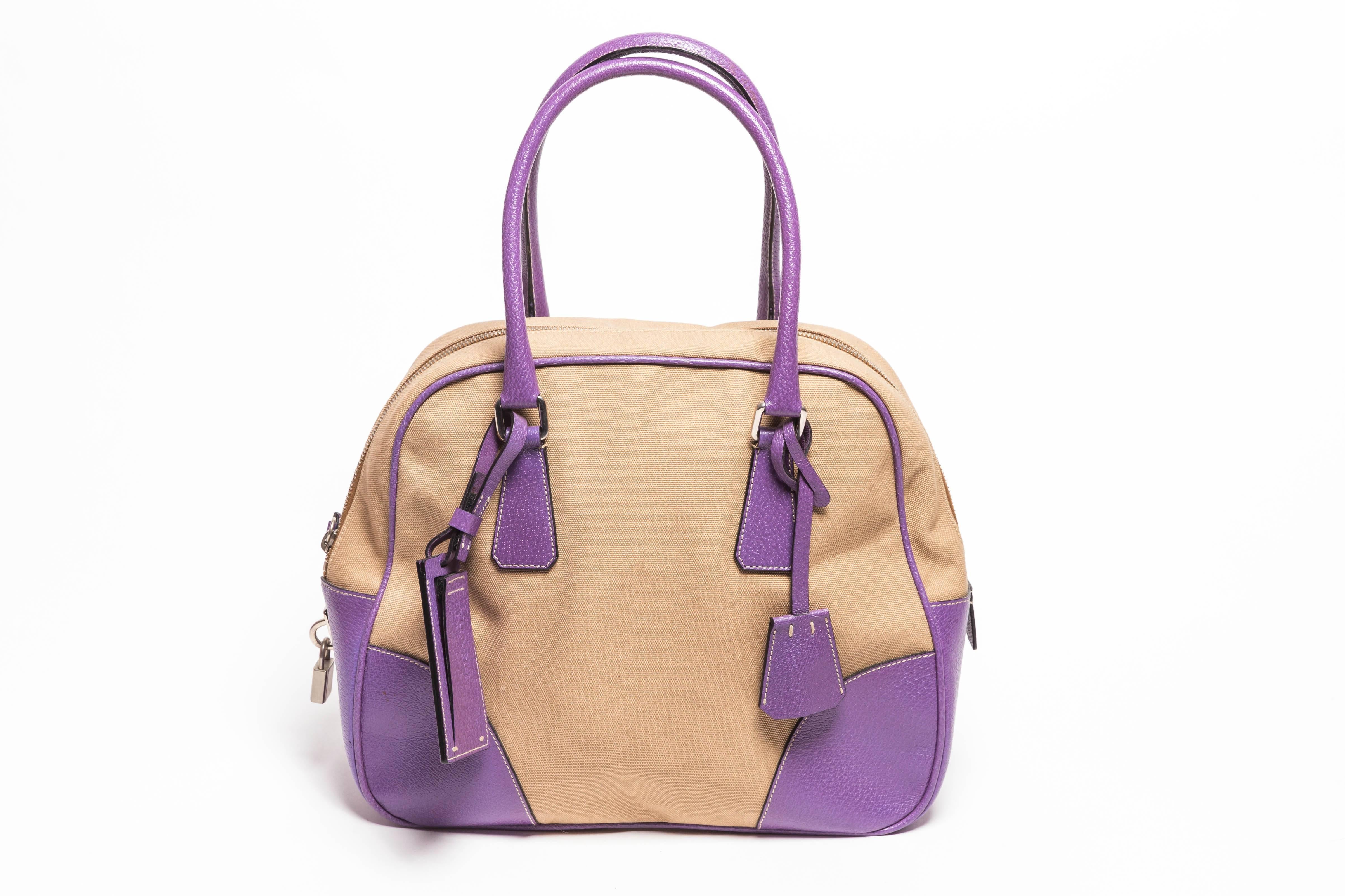 Fantastic Prada Canvas and Purple Leather Handbag with Lock, Keys and Luggage Tag
Condition is Very Good with Barely Visible Scuffs to One Corner and One Small Mark to Canvas
Canvas is Very Clean
Lined in Purple Silk with One Interior Zipper