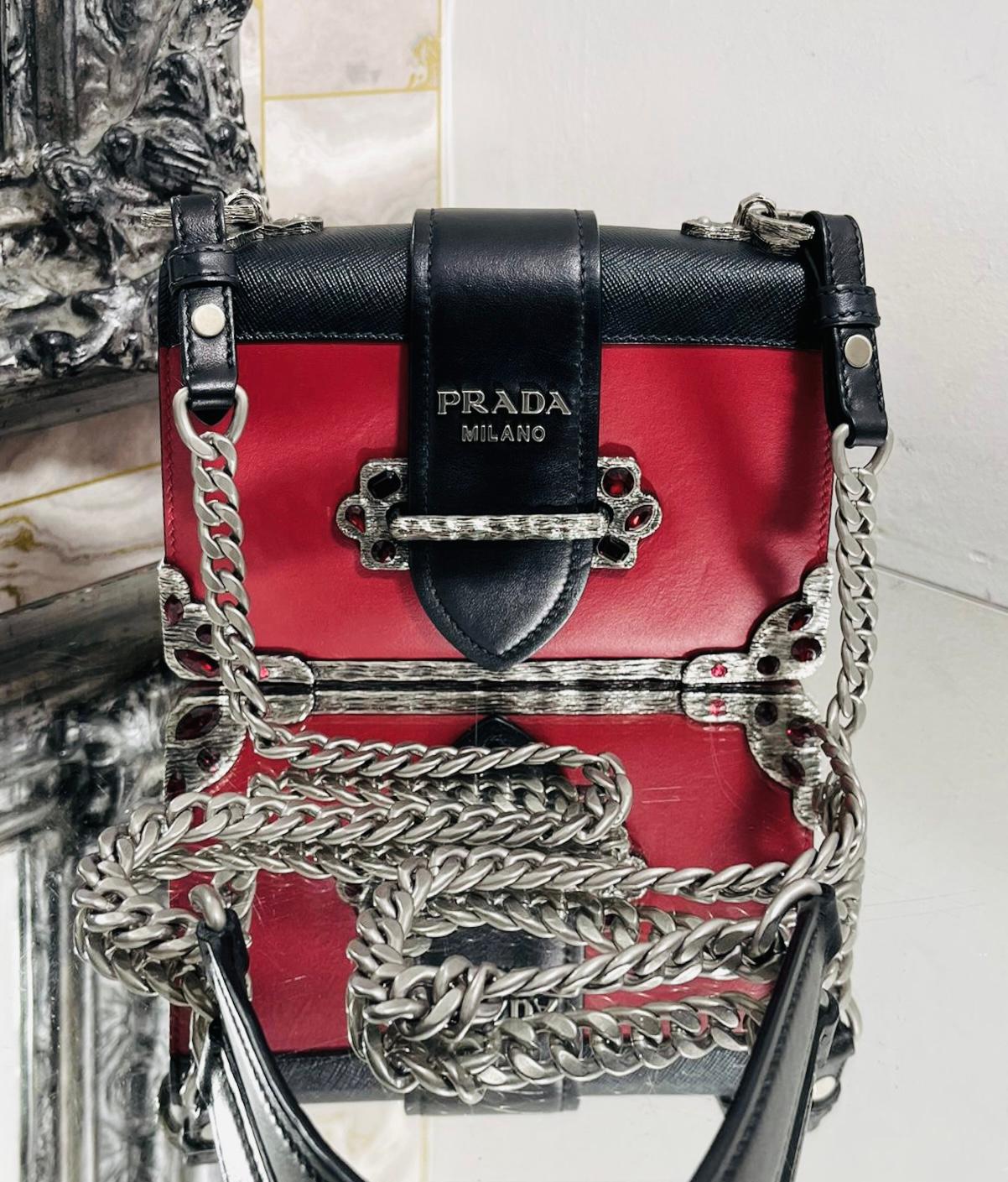 Prada Cashier Crystal Embellished Leather Bag

Red shoulder bag designed with black flap closure detailed with silver 'Prada' logo lettering.

Featuring decorative metal plating to the edges and centre embellished with red crystals.

Styled with