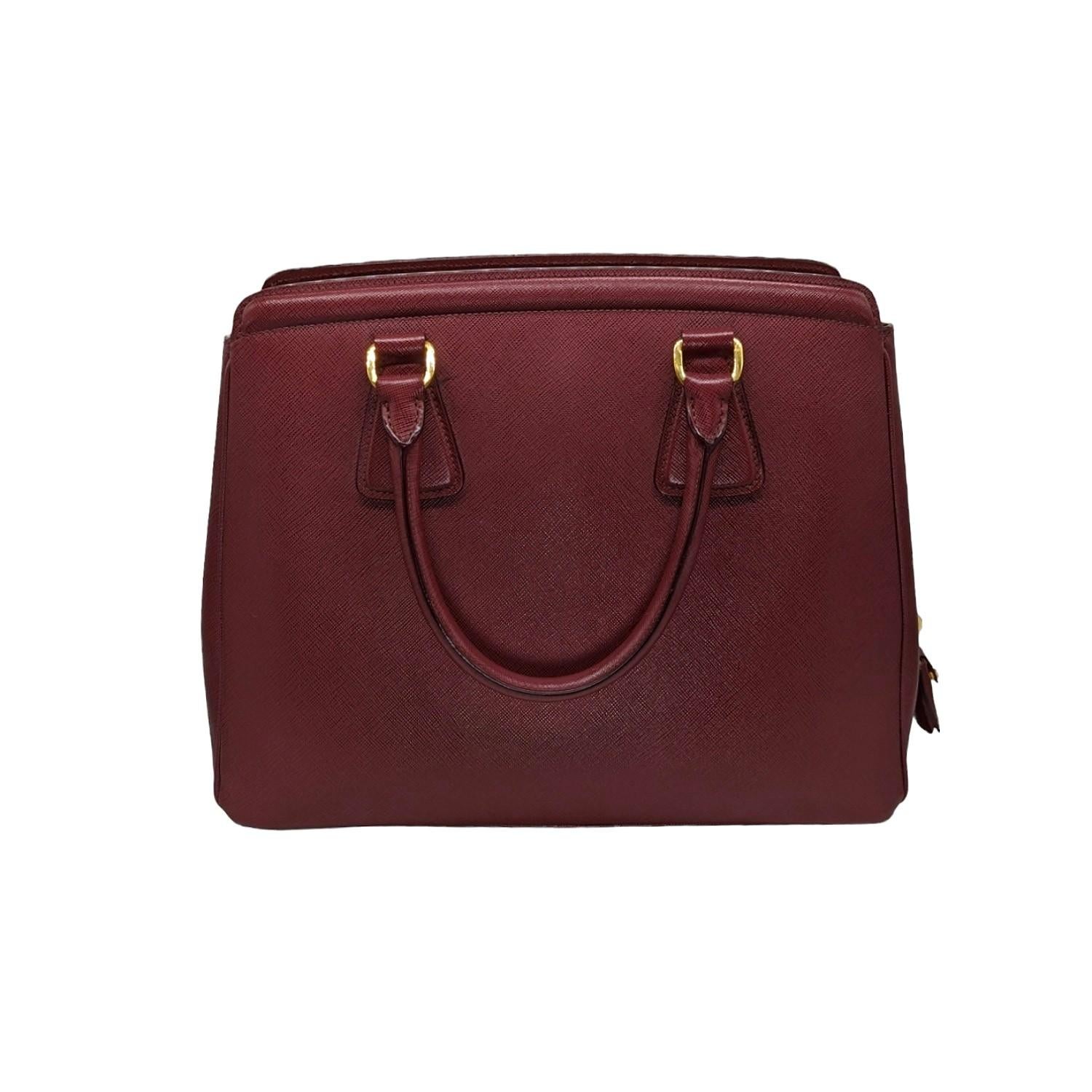 Prada Saffiano Lux Tote in Cerise. This chic tote is crafted of Saffiano cross-grain leather. The tote features rolled leather top handles, polished brass hardware. The top opens to a matching fabric interior with plenty compartments, zipper and